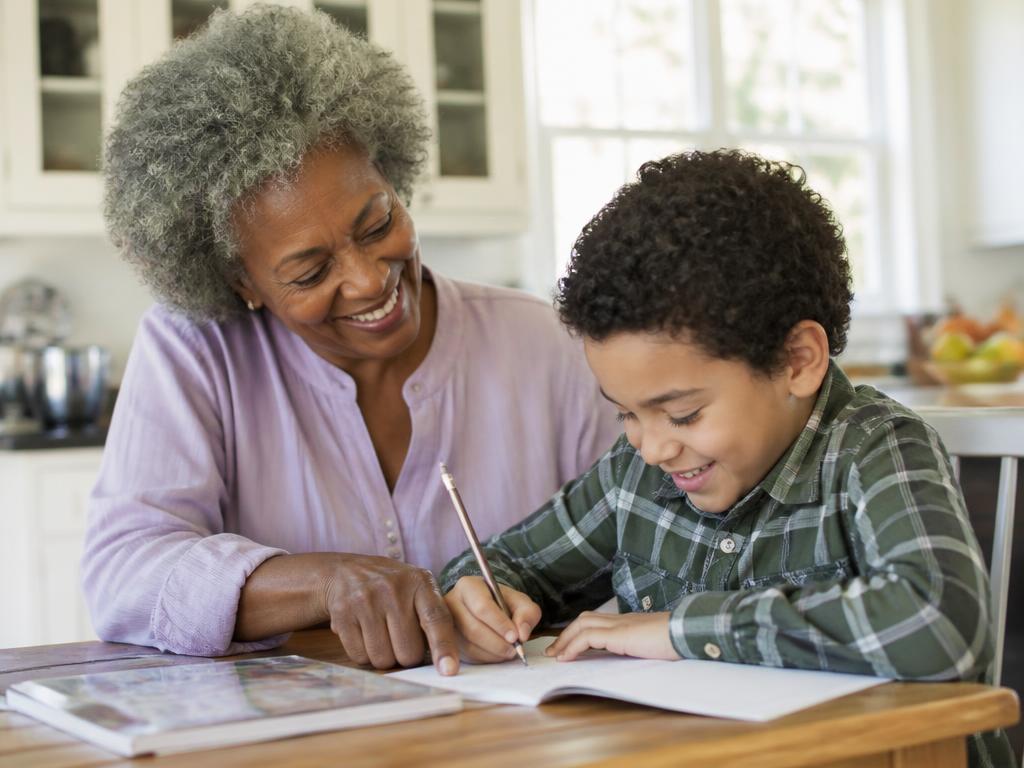 A grandmother helping her grandson with his homework at the kitchen table